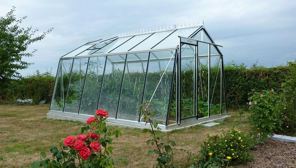 Szklarnia-ukosne Szklarnia ogrodowa z ukośnymi ścianami w ogrodzie z warzywami i roślinami